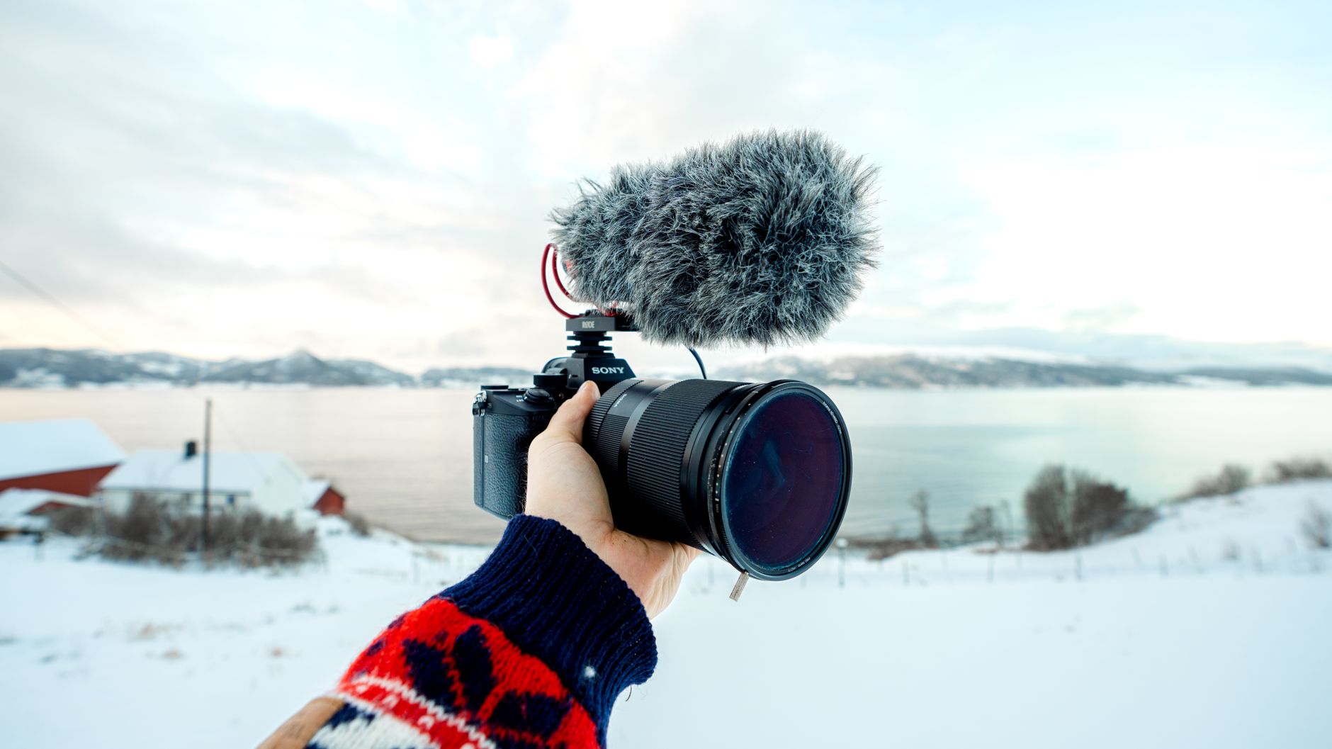Hand holding a compact camera with a mounted microphone