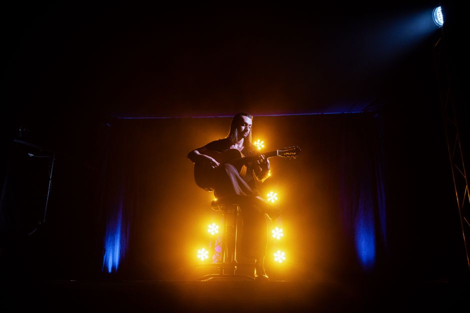 An acoustic guitar on a lit concert stage