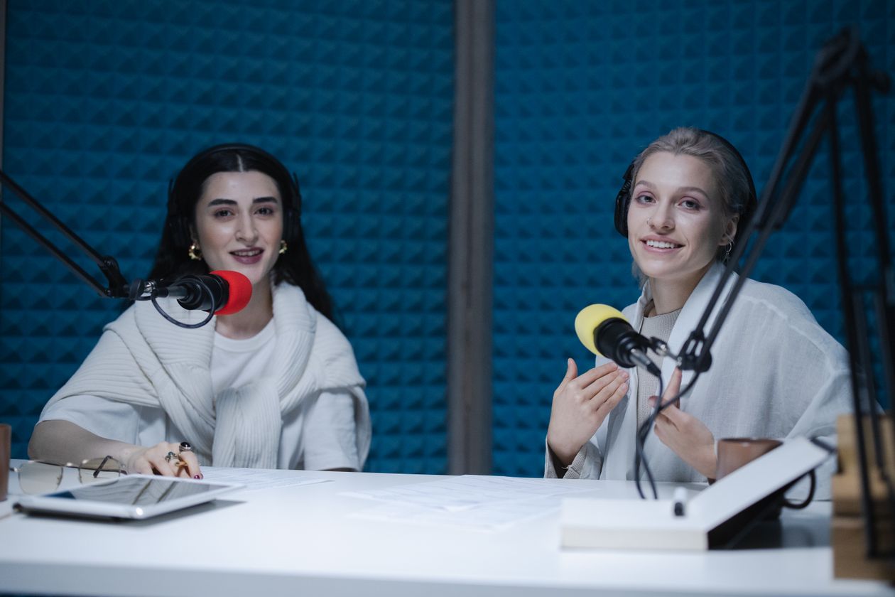 Two creators recording a podcast together with microphones